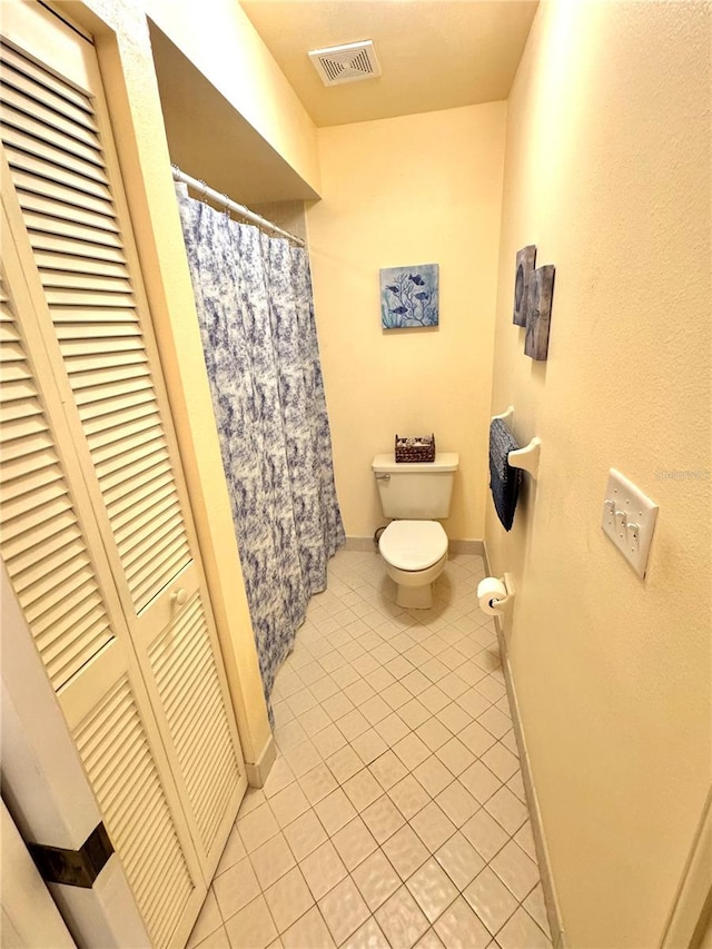 bathroom with a closet, visible vents, toilet, tile patterned flooring, and baseboards