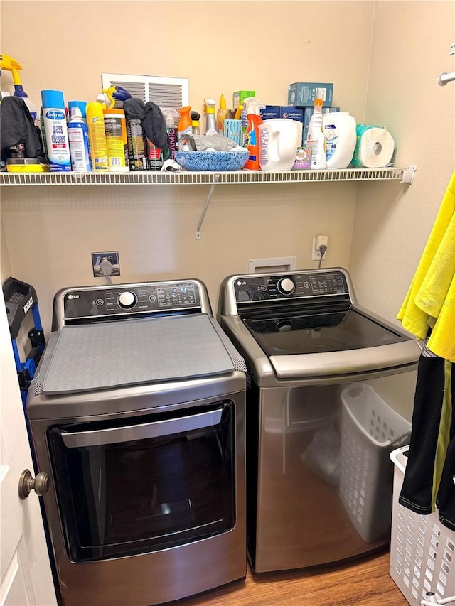 washroom featuring wood finished floors, laundry area, and separate washer and dryer