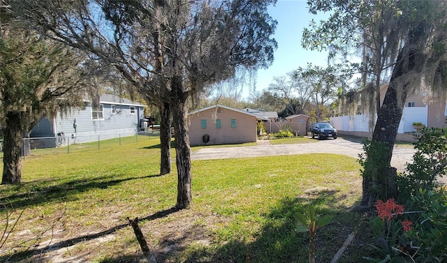 view of yard with concrete driveway and fence