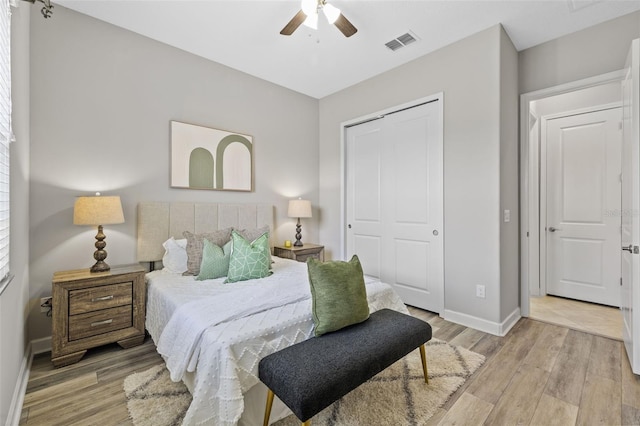 bedroom featuring light wood finished floors, a closet, visible vents, ceiling fan, and baseboards