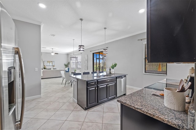 kitchen featuring dark stone counters, a center island, decorative light fixtures, stainless steel appliances, and a sink