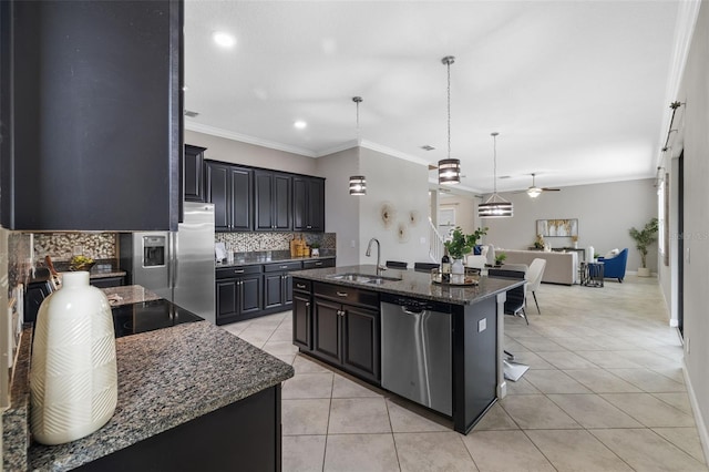 kitchen featuring stainless steel appliances, a sink, a kitchen breakfast bar, an island with sink, and dark stone countertops