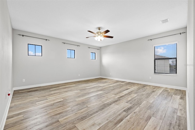 unfurnished room featuring light wood-type flooring, a healthy amount of sunlight, ceiling fan, and baseboards