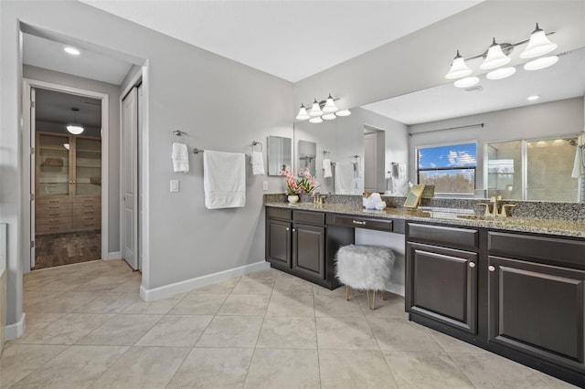 bathroom featuring a spacious closet, a stall shower, vanity, tile patterned flooring, and baseboards