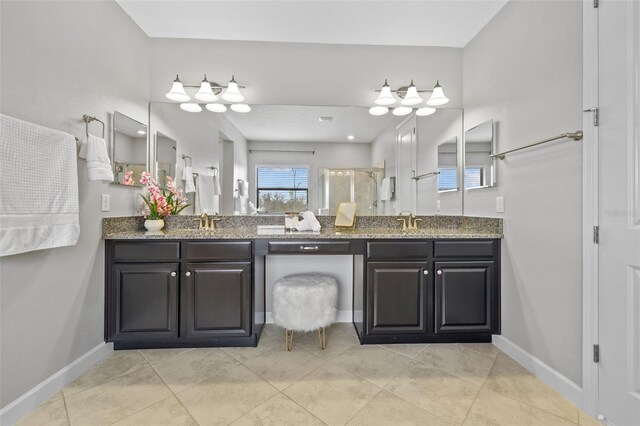 bathroom with a stall shower, a sink, baseboards, and double vanity