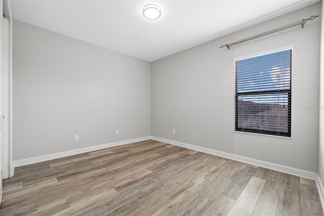 spare room with baseboards and wood finished floors