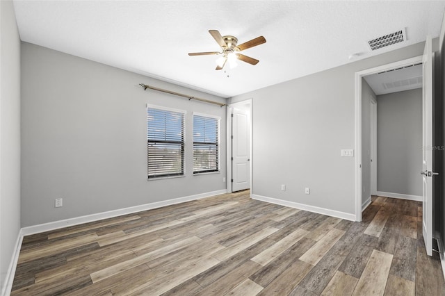 unfurnished room featuring a ceiling fan, baseboards, visible vents, and wood finished floors