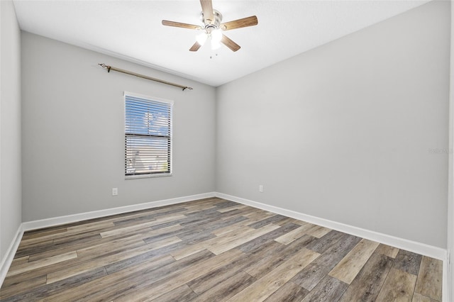 empty room with ceiling fan, wood finished floors, and baseboards