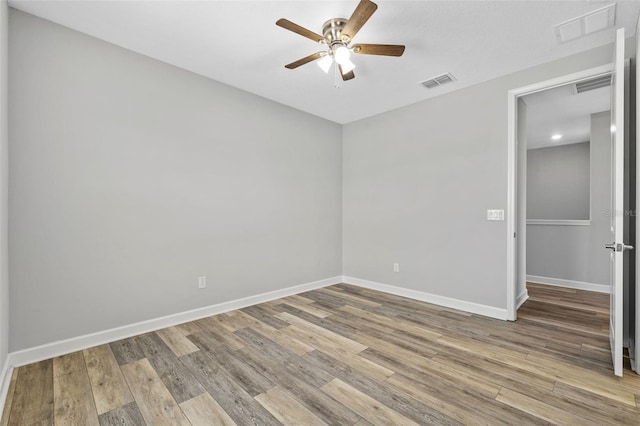 empty room featuring light wood finished floors, baseboards, and visible vents