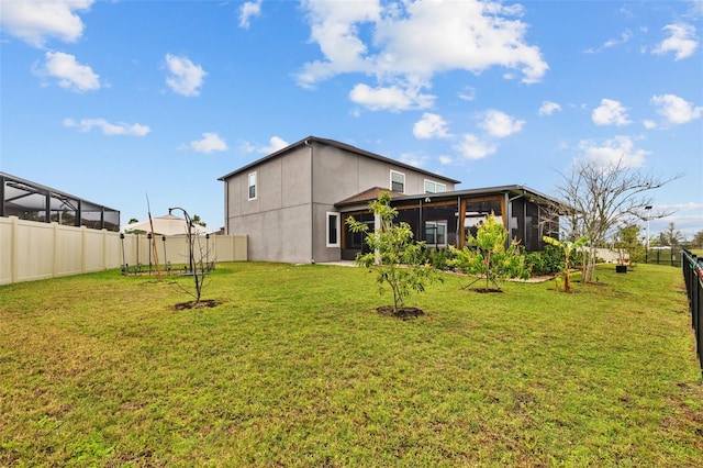 rear view of house featuring a sunroom, a fenced backyard, a lawn, and stucco siding