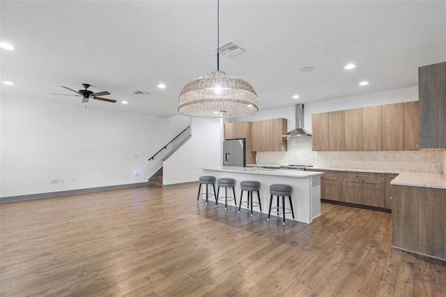 1110 25th St N, Saint Petersburg, FL 33713 - kitchen with visible vents, hanging light fixtures, a kitchen island with sink, stainless steel fridge, and wall chimney exhaust hood