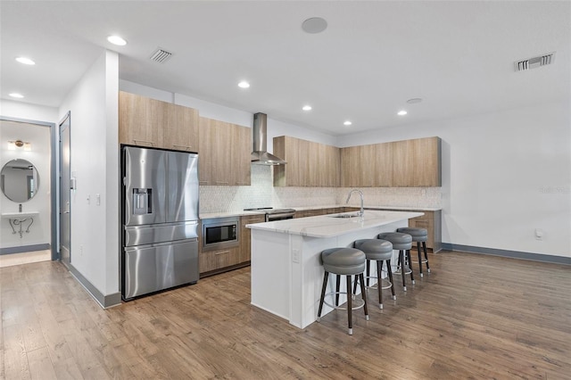 1110 25th St N, Saint Petersburg, FL 33713 - kitchen featuring a breakfast bar area, visible vents, appliances with stainless steel finishes, wall chimney range hood, and an island with sink
