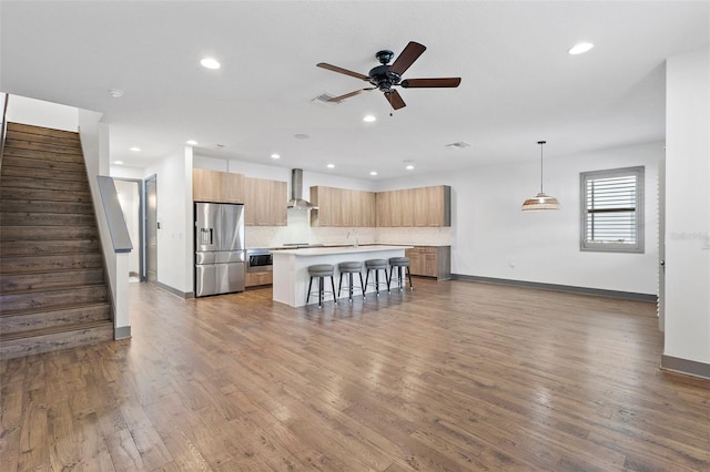 1110 25th St N, Saint Petersburg, FL 33713 - kitchen with a breakfast bar area, a kitchen island, stainless steel refrigerator with ice dispenser, wall chimney exhaust hood, and modern cabinets