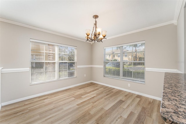 empty room with light wood finished floors, baseboards, crown molding, and an inviting chandelier