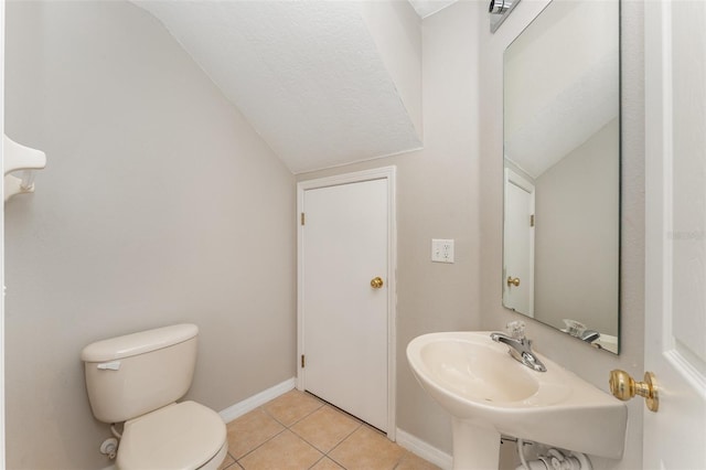 bathroom featuring tile patterned flooring, toilet, a sink, baseboards, and vaulted ceiling