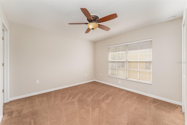 spare room with light colored carpet, ceiling fan, and baseboards