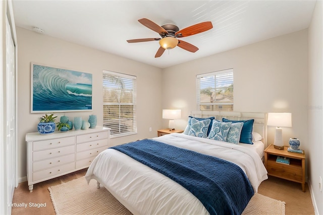 bedroom with light wood finished floors, a ceiling fan, and baseboards