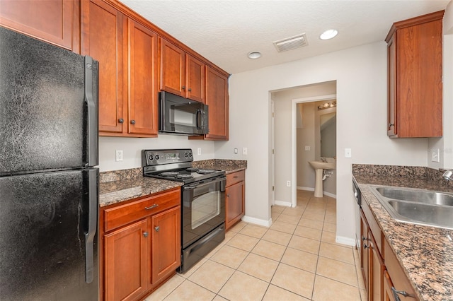 kitchen featuring light tile patterned floors, baseboards, visible vents, black appliances, and a sink