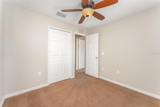 unfurnished bedroom featuring light carpet, a closet, visible vents, and baseboards