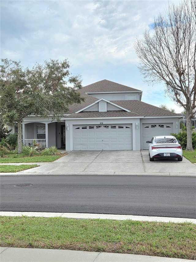 traditional home with a garage, concrete driveway, covered porch, and stucco siding