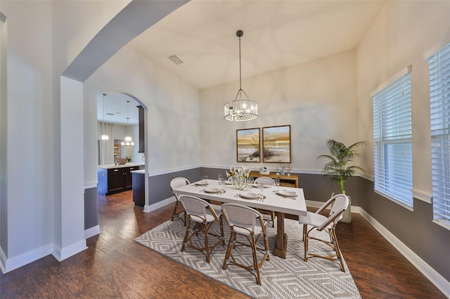 dining room featuring arched walkways, visible vents, dark wood finished floors, and baseboards