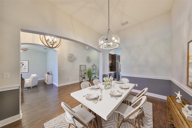 dining room featuring arched walkways, dark wood-style flooring, and an inviting chandelier