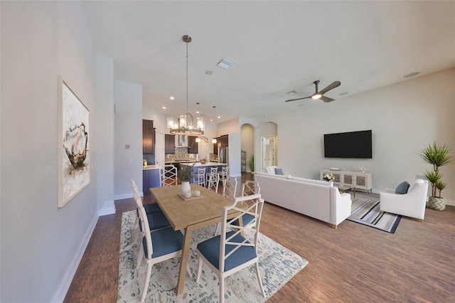 dining area featuring baseboards, visible vents, arched walkways, dark wood-style floors, and ceiling fan with notable chandelier