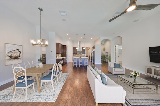 interior space with visible vents, arched walkways, baseboards, dark wood-style floors, and ceiling fan with notable chandelier