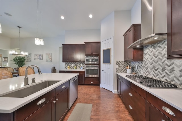 kitchen featuring light countertops, wall chimney range hood, a sink, and appliances with stainless steel finishes