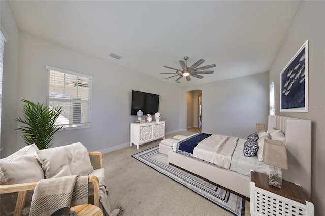 bedroom with baseboards, visible vents, arched walkways, ceiling fan, and carpet flooring