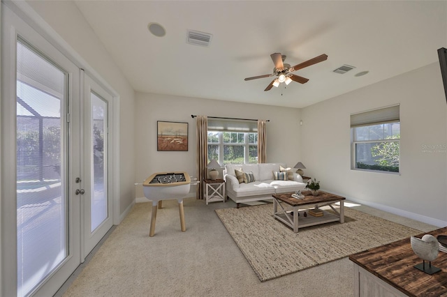 living room with baseboards, plenty of natural light, visible vents, and light colored carpet