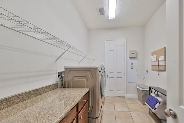 laundry area featuring light tile patterned floors, a textured ceiling, laundry area, visible vents, and washing machine and clothes dryer