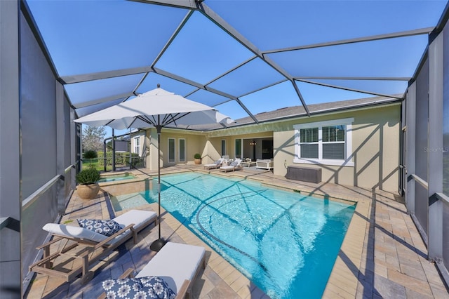 view of pool with glass enclosure, a patio, and a pool with connected hot tub