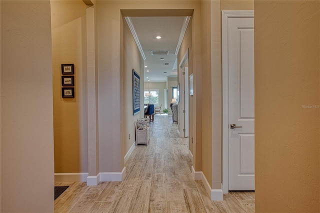 hall with recessed lighting, visible vents, baseboards, ornamental molding, and light wood-type flooring