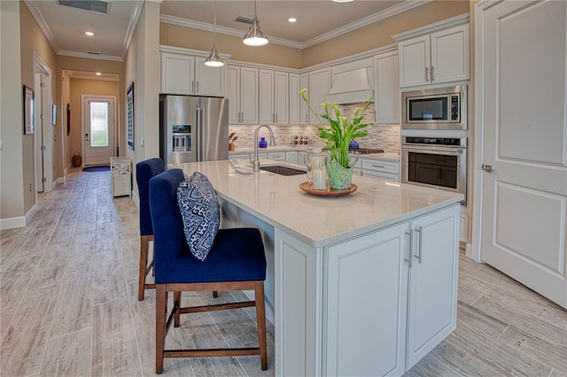 kitchen featuring a kitchen island with sink, appliances with stainless steel finishes, a sink, and white cabinetry