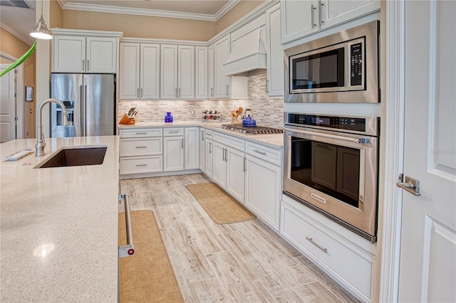 kitchen featuring light stone counters, hanging light fixtures, stainless steel appliances, white cabinetry, and a sink