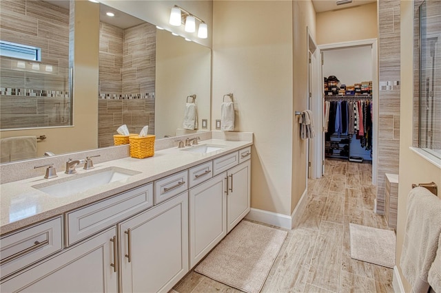 bathroom featuring a walk in shower, a sink, a spacious closet, and double vanity