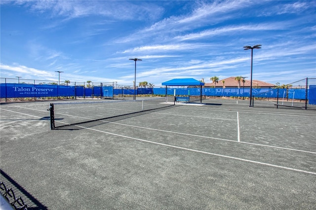 view of sport court featuring a water view and fence