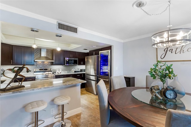 kitchen with tasteful backsplash, visible vents, wall chimney exhaust hood, appliances with stainless steel finishes, and a tray ceiling