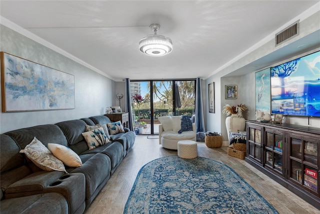 living area featuring ornamental molding, a wall of windows, wood finished floors, and visible vents