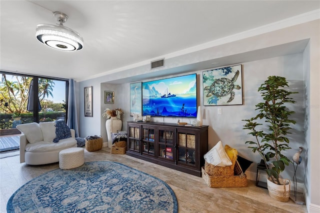 living area with baseboards, visible vents, and crown molding