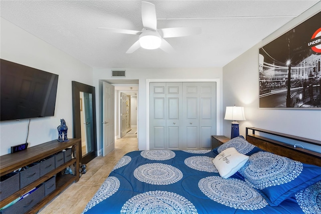 bedroom featuring a closet, visible vents, a ceiling fan, a textured ceiling, and wood finished floors