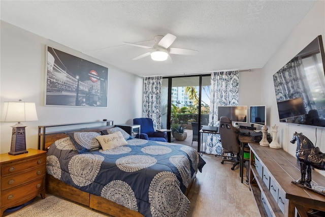 bedroom featuring expansive windows, ceiling fan, a textured ceiling, and wood finished floors