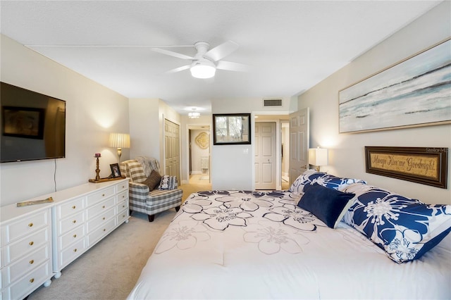 bedroom featuring light carpet, ceiling fan, visible vents, and ensuite bathroom