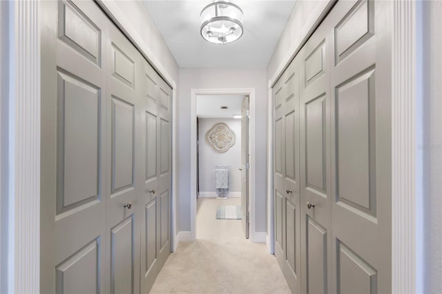 hall featuring light carpet, baseboards, and a textured ceiling