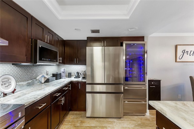 kitchen featuring a tray ceiling, appliances with stainless steel finishes, visible vents, and light stone countertops