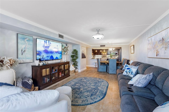 living room featuring baseboards, light wood-style flooring, visible vents, and crown molding