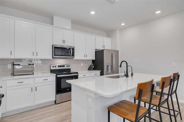 kitchen featuring stainless steel appliances, a sink, and a kitchen island with sink