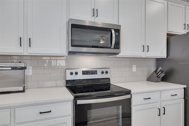 kitchen featuring light stone counters, appliances with stainless steel finishes, white cabinets, and backsplash