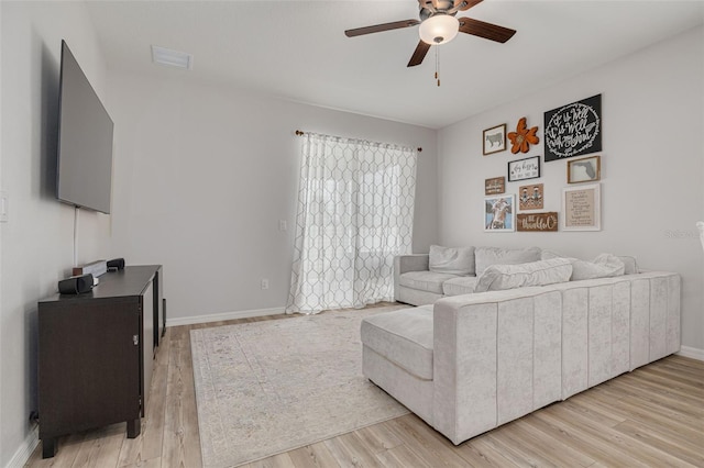 living room with light wood-style floors, visible vents, baseboards, and a ceiling fan